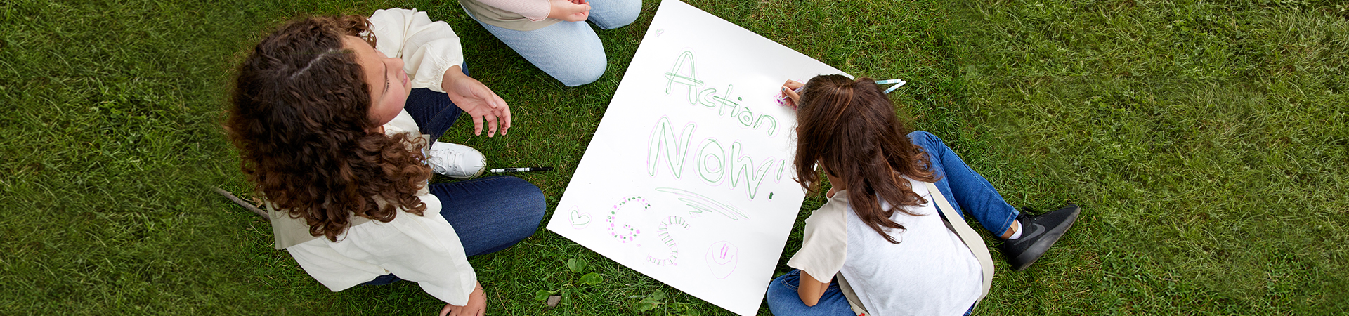  young girls making poster with text that reads action now girl scouts 